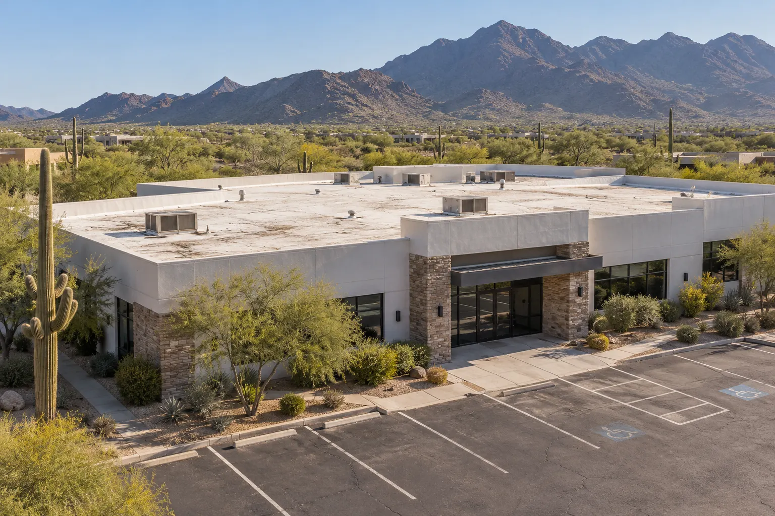 Single-story stucco and stone office building with a flat roof and rooftop units
